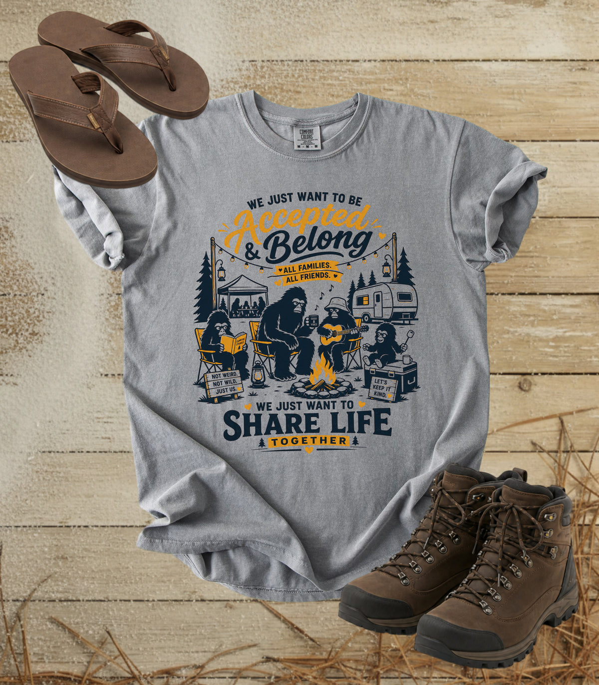 A comfort colors grey color graphic t-shirt featuring a camping scene with bigfoot and the text 'We Just Want To Be Accepted & Belong.